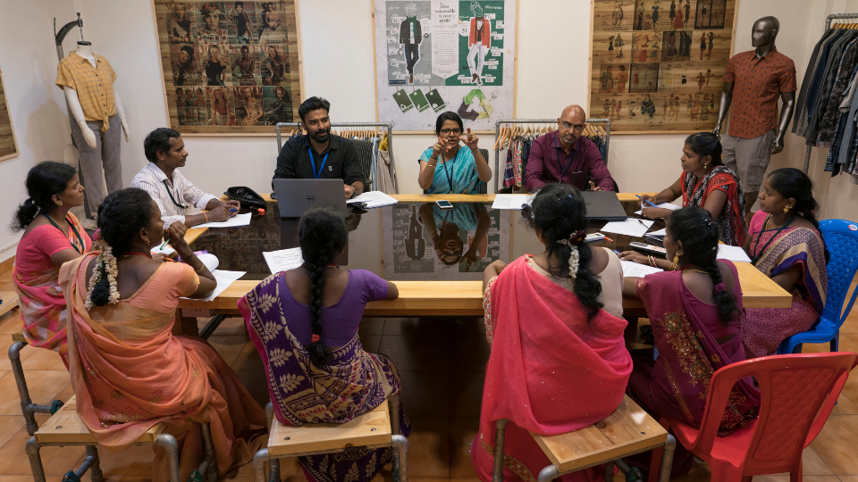 A group of workers at a Fair Trade Certified factory gathered around a table counting paper ballots.